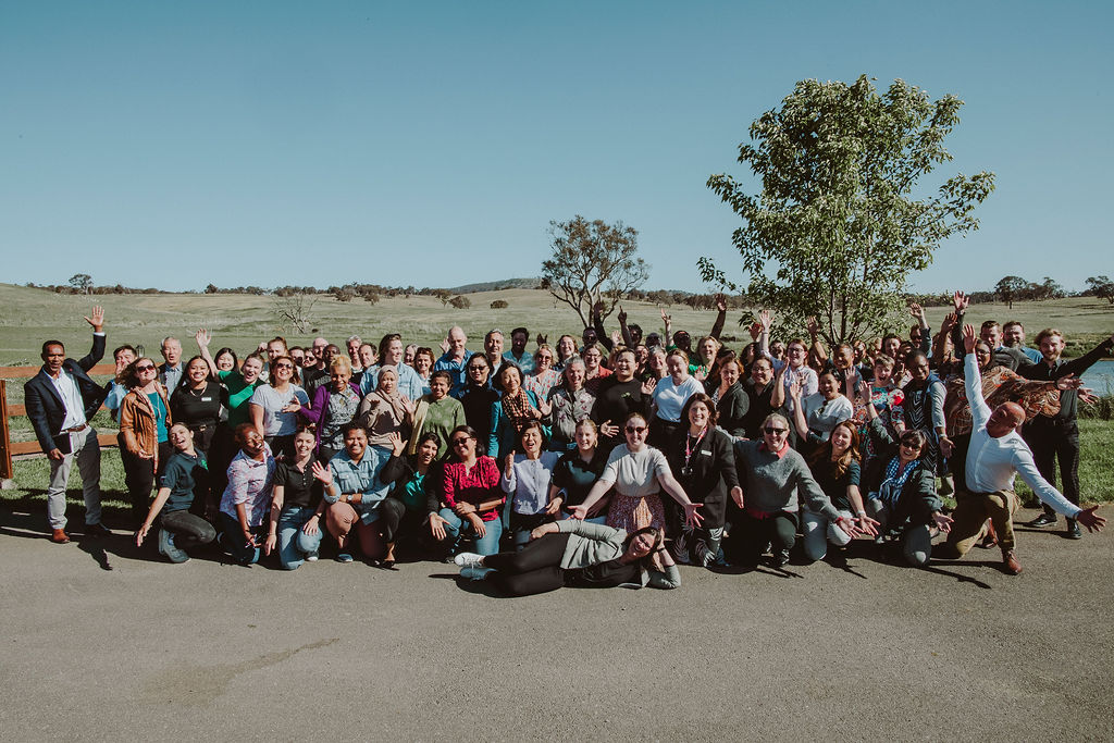 A large group of workshop participants celebrating together outdoors
